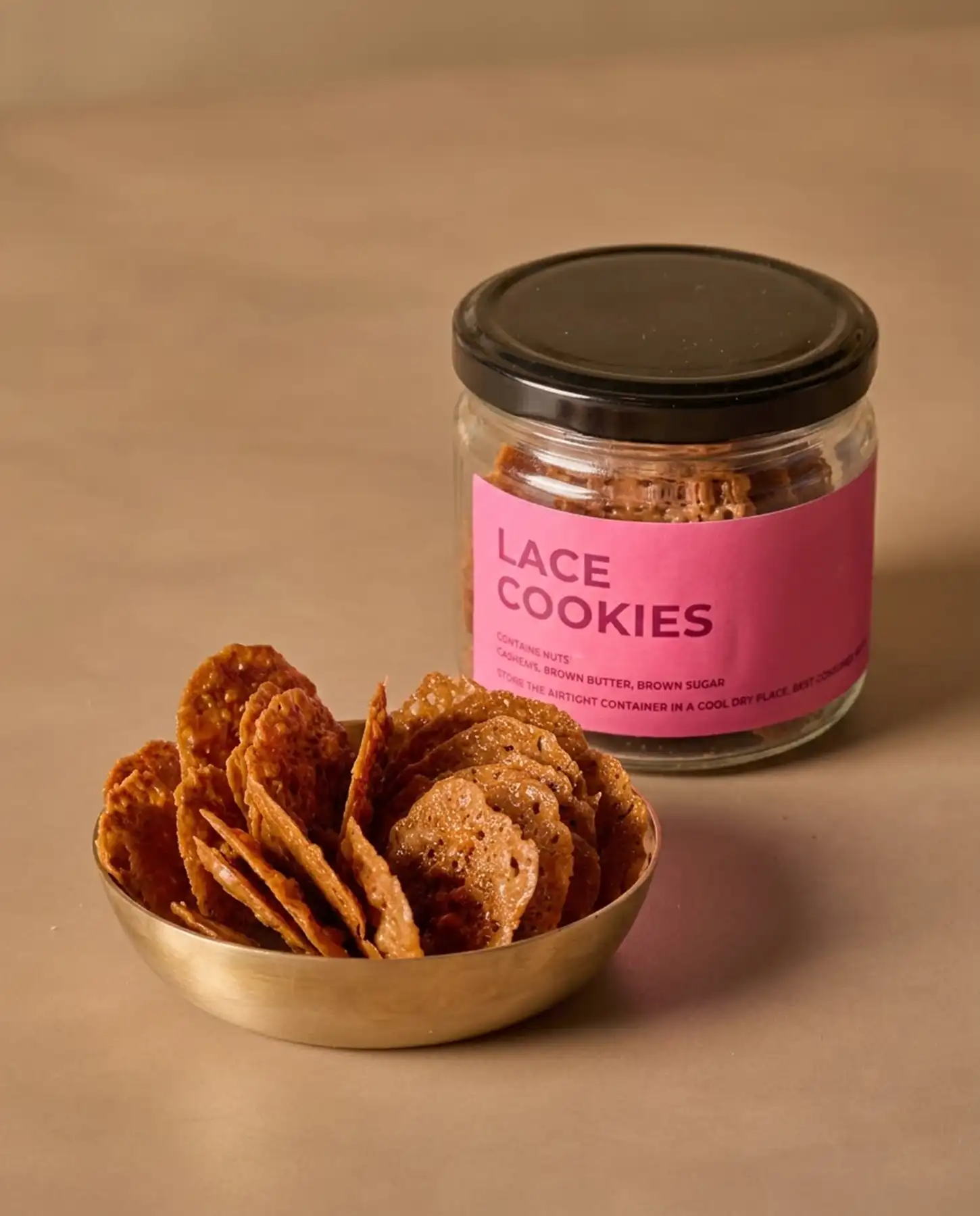 Choti Diwali Basket 3 A metal bowl filled with thin, crispy lace cookies next to a glass jar labeled Lace Cookies containing more of the same cookies.